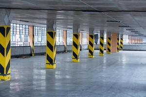 Spacious underground parking garage boasts modern design with striped yellow pillars and polished concrete floors for urban transport photo