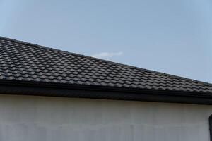 New roof installation features modern tiles on a residential home with a cloudy sky in the background, highlighting the construction work photo