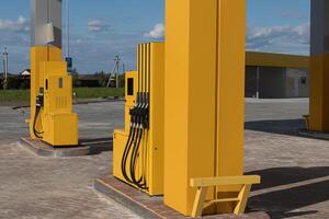 Fuel dispensers are positioned at a gas station, with nozzles ready for vehicles to refuel on a bright, clear day photo