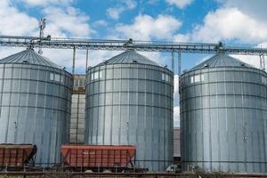Several large metal grain silos stand at an agricultural site, designed for storing harvested crops like grain photo
