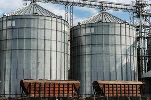Large silos stand tall at a grain storage facility, where harvested crops are stored for future use. The sun brightens the industrial scene photo