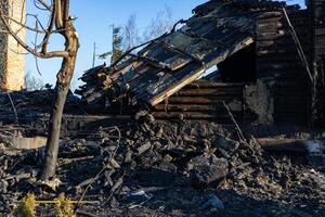 A significant fire has destroyed a wooden structure, leaving behind a heavily damaged site with ash and debris scattered everywhere photo