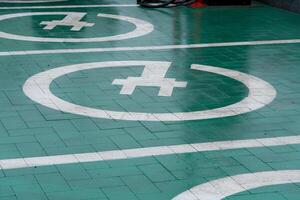 Green pavement features marked parking spaces with white symbols, indicating a designated area for specific vehicles in a busy urban environment photo