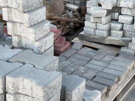 Various concrete blocks are stacked on wooden pallets, waiting for transport to a construction area during daylight photo
