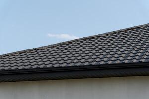 Close-up view of a modern tiled roof against a clear sky, highlighting the intricate patterns and textures of the roofing material photo