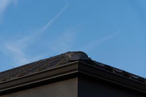 A black roof structure is visible against a clear blue sky, showcasing its sleek design during the day with no obstructions photo