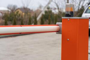 A security barrier stands at the entrance of a parking lot, ensuring controlled access to vehicles in a suburban neighborhood on a cloudy day photo
