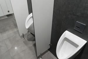 Clean and minimalist restroom design showcases white urinals beside privacy partitions in a contemporary urban environment photo