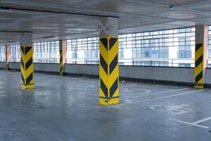 Empty parking garage showcases yellow striped columns with sleek, large windows visible in the background, highlighting an urban environment photo