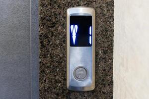 Digital numbers illuminate as the elevator waits for passengers in a modern office building's sleek lobby during peak hours photo