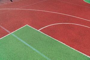 Brightly colored sports court features a mix of red and green surfaces, offering a lively backdrop for athletic activities on a sunny day photo