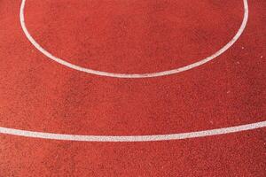 Smooth red track surface features clean white lines forming a perfect circle under clear blue skies, inviting athletes to train photo
