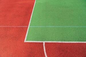 Two distinct sections of a sports court show bright red and green surfaces, lined with white markings under sunny conditions photo