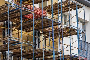Workers prepare scaffolding around a building for renovation tasks while ensuring safety and accessibility for construction efforts photo