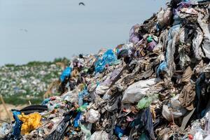 A massive heap of assorted garbage accumulates under clear skies, showcasing the ongoing challenge of waste disposal and recycling photo