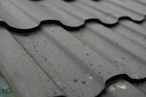 Raindrops bead on the surface of sleek metallic tiles, reflecting the artistry of modern roof design in a residential setting photo