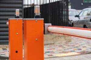 Access to the parking lot is controlled by a bright orange automatic barrier, enhancing safety and security at the entrance photo