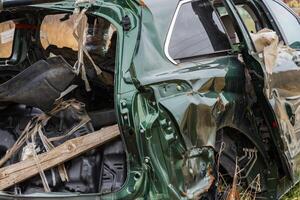 A damaged car is left abandoned on the side of a suburban road, highlighting the consequences of a severe crash and the need for safety photo