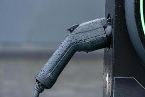 Raindrops glisten on an electric vehicle charging handle, highlighting a commitment to sustainable energy and modern transportation in cities photo