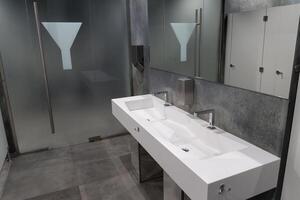 Contemporary restroom showcasing a spacious design with minimalist aesthetics, emphasizing cleanliness and functionality for public use photo