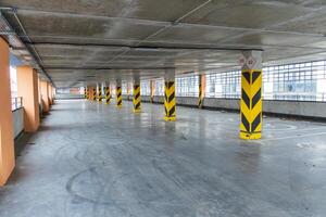 Brightly lit underground parking garage with ample marked parking spaces and structural pillars, designed for urban transport needs photo