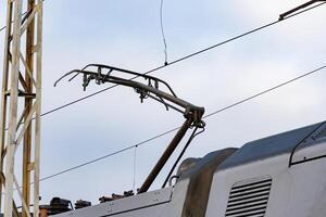 A close-up view of an electric train's pantograph raising to make contact with the overhead line for power at a railway station photo