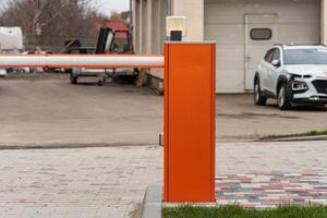 An automatic barrier gate stands closed at a parking lot entrance, ensuring secure access for vehicles at this commercial location photo