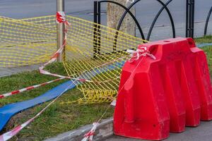 Construction work is in progress in the city, marked by a red barrier and caution tape to ensure pedestrian safety near the site photo
