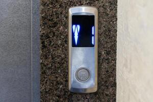 Control panel displays illuminated buttons indicating elevator direction and floor selection in a contemporary apartment environment photo