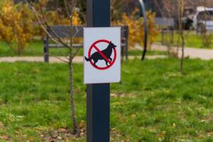 A warning sign stands in a park indicating that dogs are not allowed, highlighting the importance of clean outdoor spaces for visitors photo