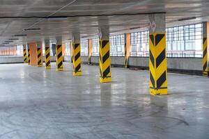 Spacious underground parking area featuring yellow and black striped columns, designed for efficient vehicle storage and easy access photo