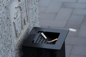 Cigarette butts are discarded in a waste container, emphasizing the ongoing need for better waste management practices in urban areas photo