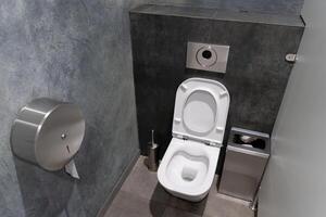 A modern restroom showcases a minimalistic toilet and efficient waste disposal unit against a backdrop of clean grey walls and sleek design photo