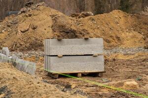 Stacked concrete blocks sit on a pallet within a gravel path at a construction site in an urban environment, indicating ongoing repairs photo