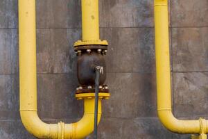 Yellow metal pipes and valves showcase a gas pipeline connection within an industrial infrastructure, highlighting energy transportation technology photo