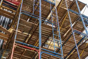 Workers utilize scaffolding to build a multi-story structure, showcasing essential equipment in the construction industry at a bustling site photo