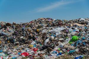 Large landfill filled with plastic garbage and debris highlights pollution issues impacting the environment under clear blue skies photo