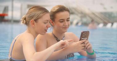 Cute Joyful Ladies Viewing Pictures In Modern Smartphone When Relaxing In Swimming Pool In SPA video