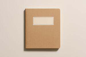 Closed brown kraft notebook with blank label on beige background. Minimal stationery mockup for branding or identity design photo