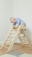 A joyful toddler explores a wooden climbing frame at the park, enhancing their physical development and motor skills in a safe and engaging environment for play and learning video