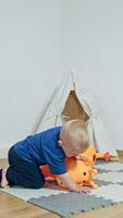 A giggling toddler joyfully plays with a bright orange giraffe toy in a colorful indoor space, showcasing the joy and imagination of early childhood exploration video