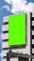 Green chroma key blank vertical billboard mock up in city center for advertising on skyscrapers with beautiful clouds background. video