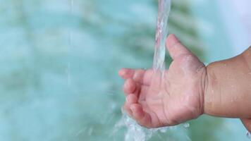Baby Hand Feeling Water Stream, Baby hand playing with flowing water. A gentle stream runs over the palm, symbolizing innocence, sensory learning, freshness, and childhood joy. Close-up video
