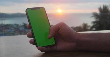 Close up man holds smartphone with green screen swipes photos or pictures at social networks. Use green screen mockup for copy space close up. Chroma key mock-up on smartphone in hand. video