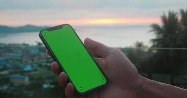 Close up man holds mobile phone with green screen swipes photos or pictures at social networks. Use green screen mockup for copy space close up. Chroma key mock-up on mobile phone in hand. video