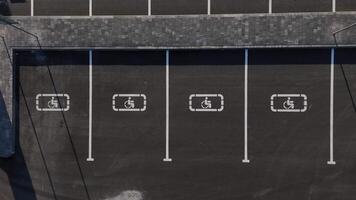 Aerial drone footage of a parking lot with designated spaces for disabled access, marked with wheelchair symbols. video