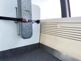 Foldable seat with seatbelt and accessibility sign for passengers with disabilities on modern electric ferry. Inclusive design and public transport infrastructure photo