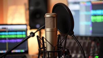 Close up of a gold microphone with a pop filter in a recording studio environment setup well video
