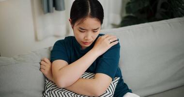 Handheld high angle view shot, Asian woman sitting alone on the sofa thinking about life problems with a stressed expression on her face. video