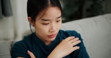 Handheld high angle view shot, Asian woman sitting alone on the sofa thinking about life problems with a stressed expression. video